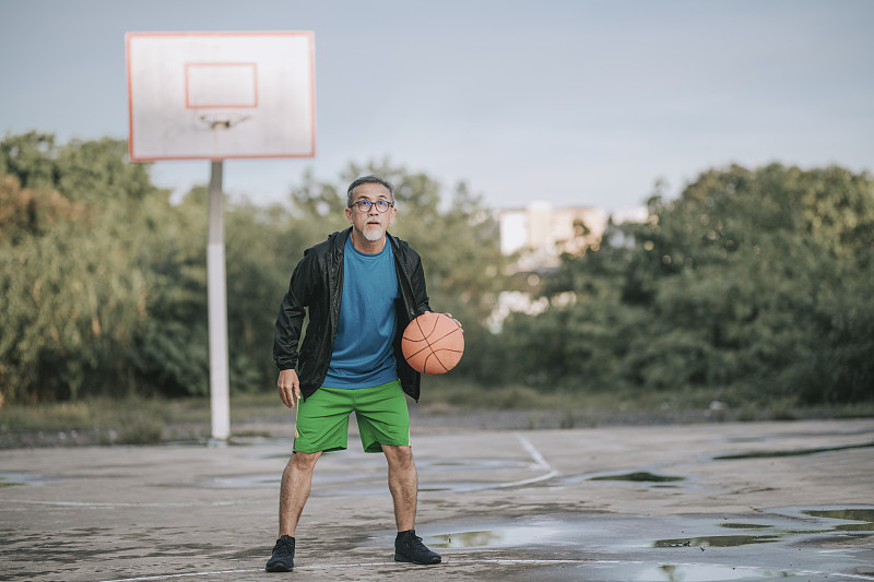 早上，一名亚裔中国男子在篮球场练习篮球比赛图片下载