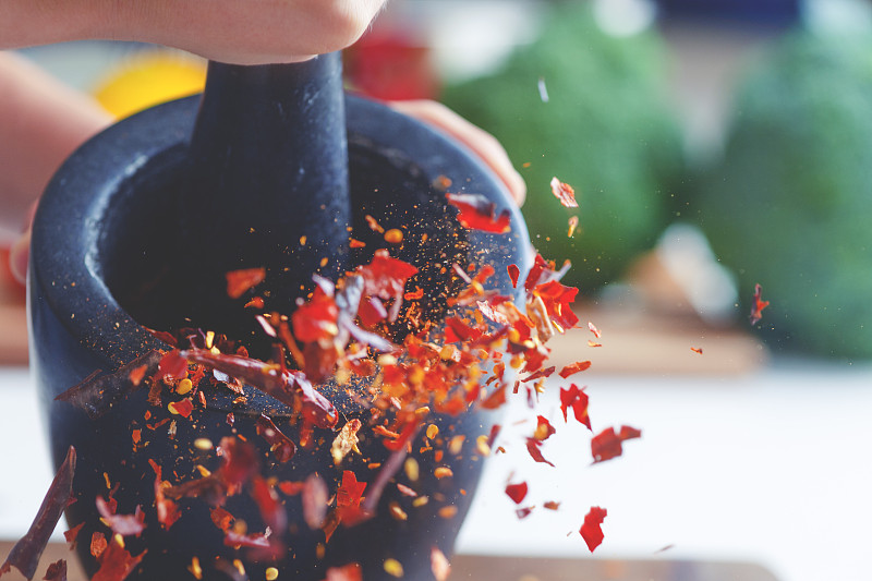 干辣椒被研钵和杵碾碎的动作画面。图片下载