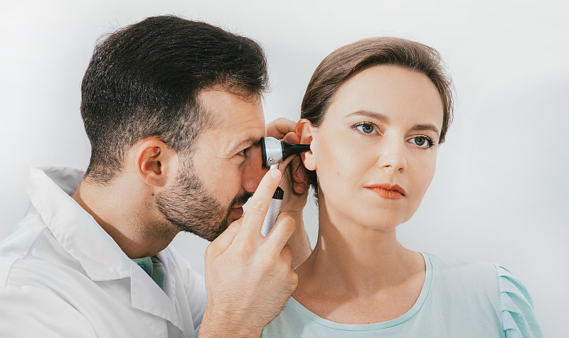 女病人在诊所接受耳朵检查，经验丰富的医生使用耳镜检查女性的耳朵图片下载