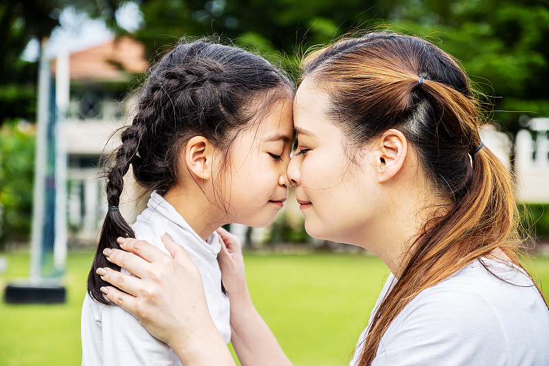 可爱的亚洲母亲和小女儿拥抱和亲吻在公园，在一起的概念，爱的家庭图片下载