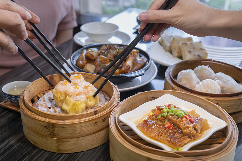 人们在餐馆里用筷子吃广东dum sum图片下载