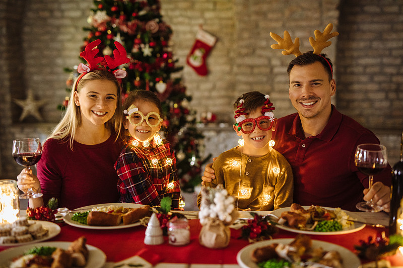 父母在餐厅与孩子们共进圣诞晚餐时喝酒敬酒图片素材