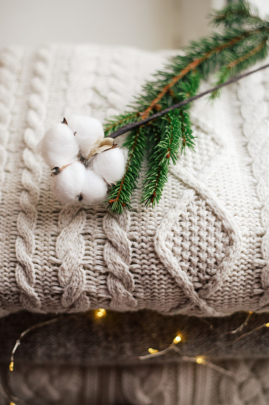 温暖的灰色针织毛衣堆放在家里的窗台上，松树和天然植物装饰圣诞节图片下载