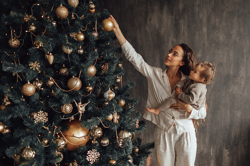 母亲和女儿在家里装饰圣诞树。图片下载