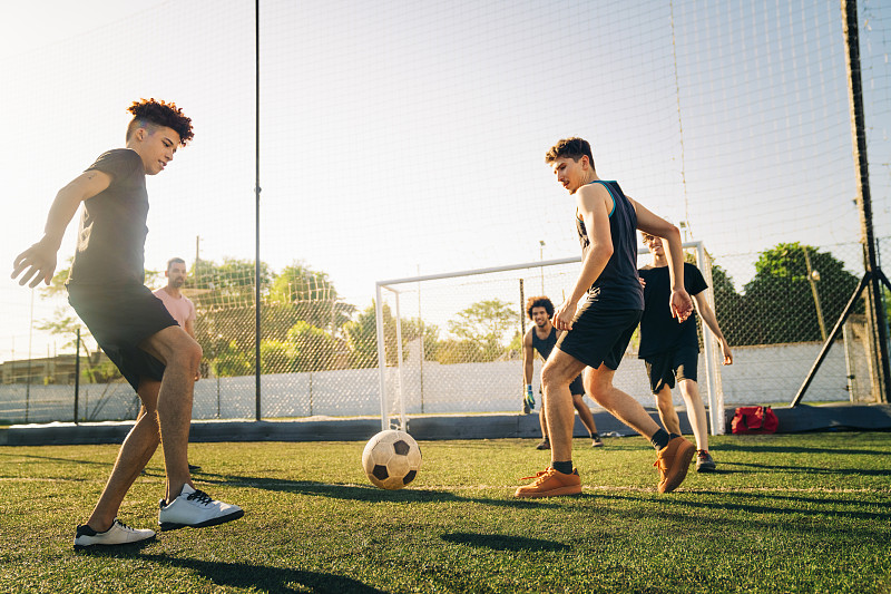 男运动员在阳光明媚的日子里踢足球图片下载