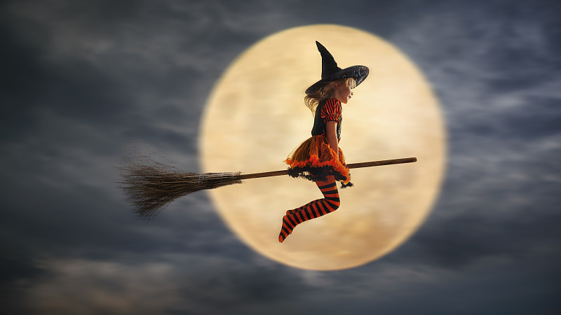 孩子扮成女巫飞到万圣节，背景是月亮图片下载