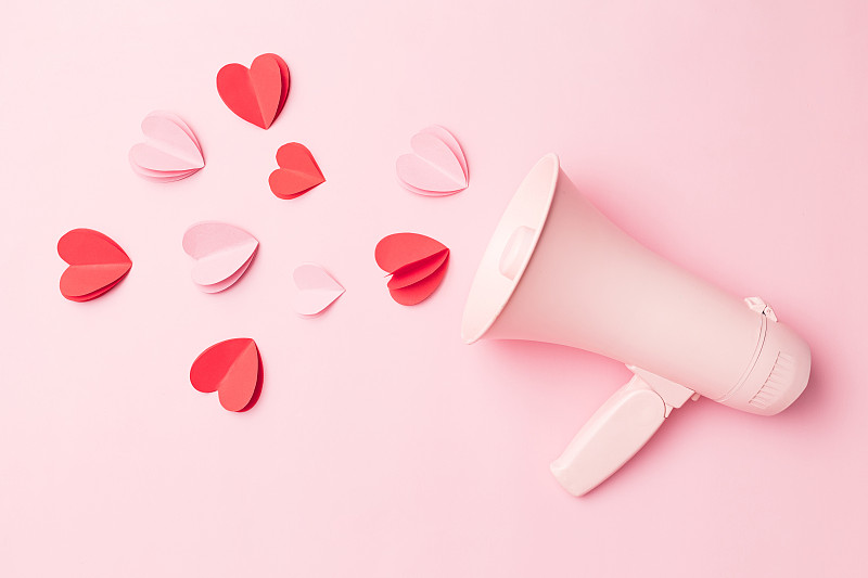 情人节背景扩音器和心形纸屑在粉红色的背景。图片下载