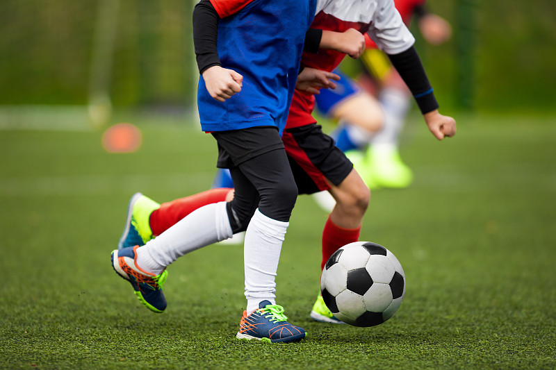 孩子们在草地上踢足球。两个学校的孩子在足球比赛中进行决斗和竞争图片下载