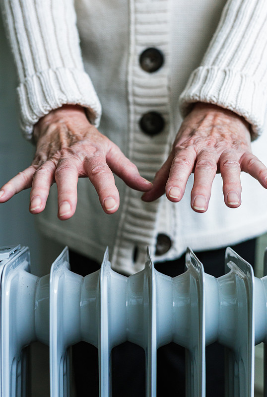 老妇人在家里用电暖炉暖手图片下载