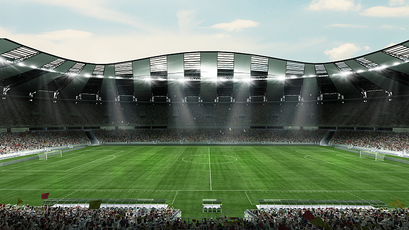 空旷的大足球场，有手电筒和晴朗多云的天空背景。看台上坐满了足球迷的体育场。图片下载