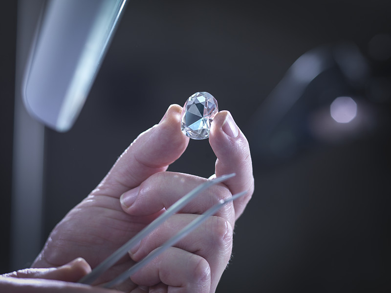 珠宝商检查手中的钻石复制品图片下载