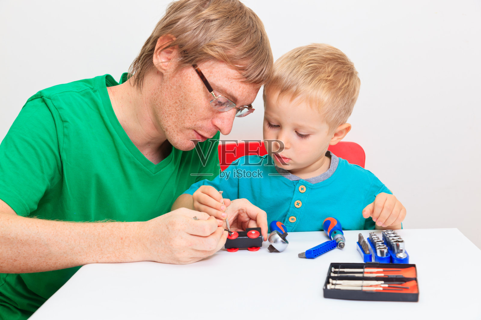 父亲教儿子如何修理玩具火车照片摄影图片