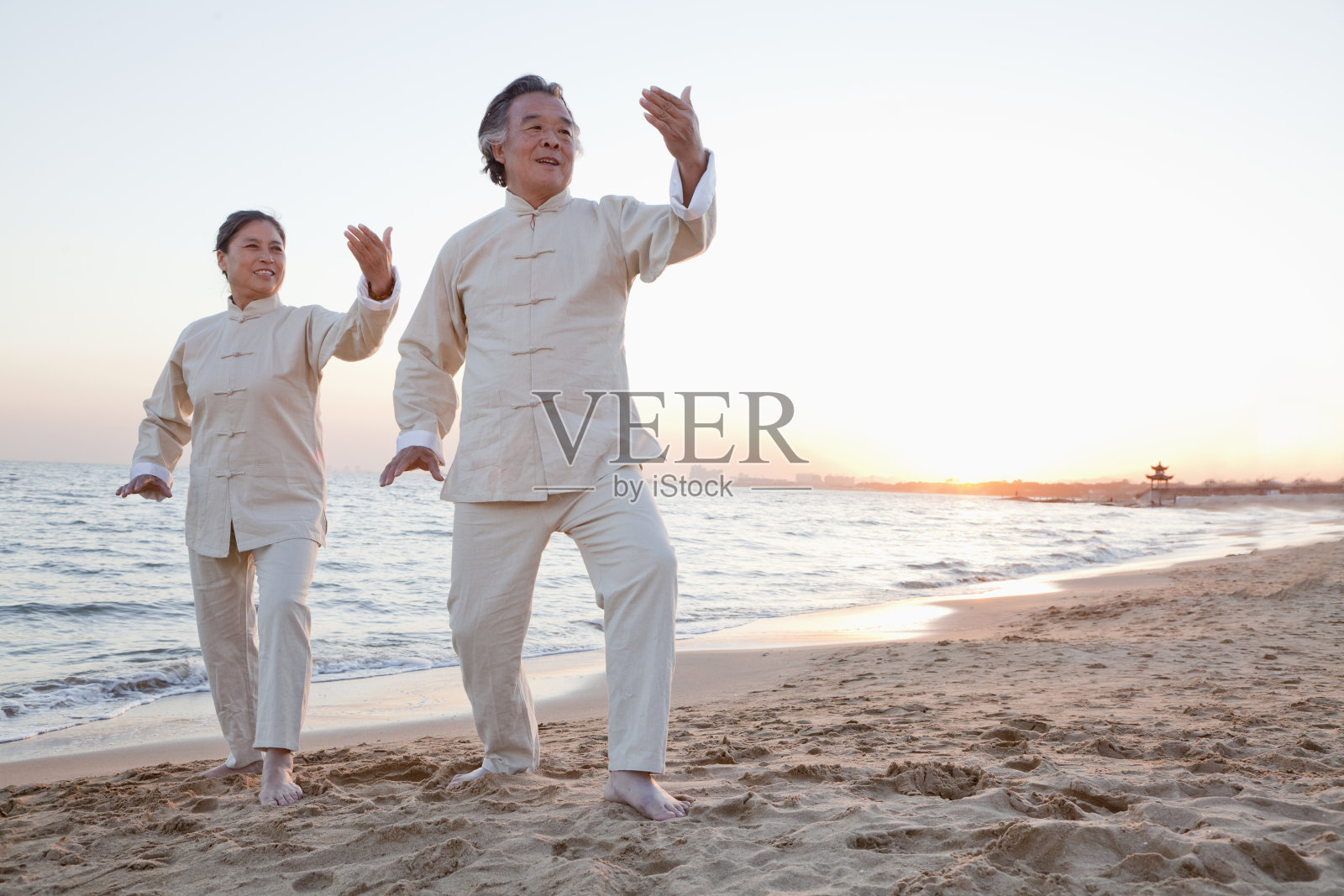 两个老人在沙滩上练习太极拳照片摄影图片