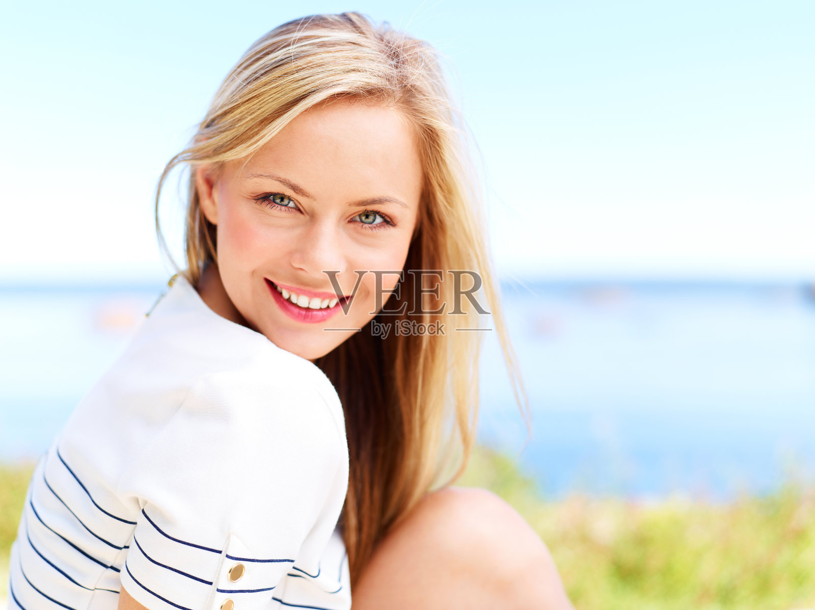 女人微笑着与草和水模糊的背景照片摄影图片