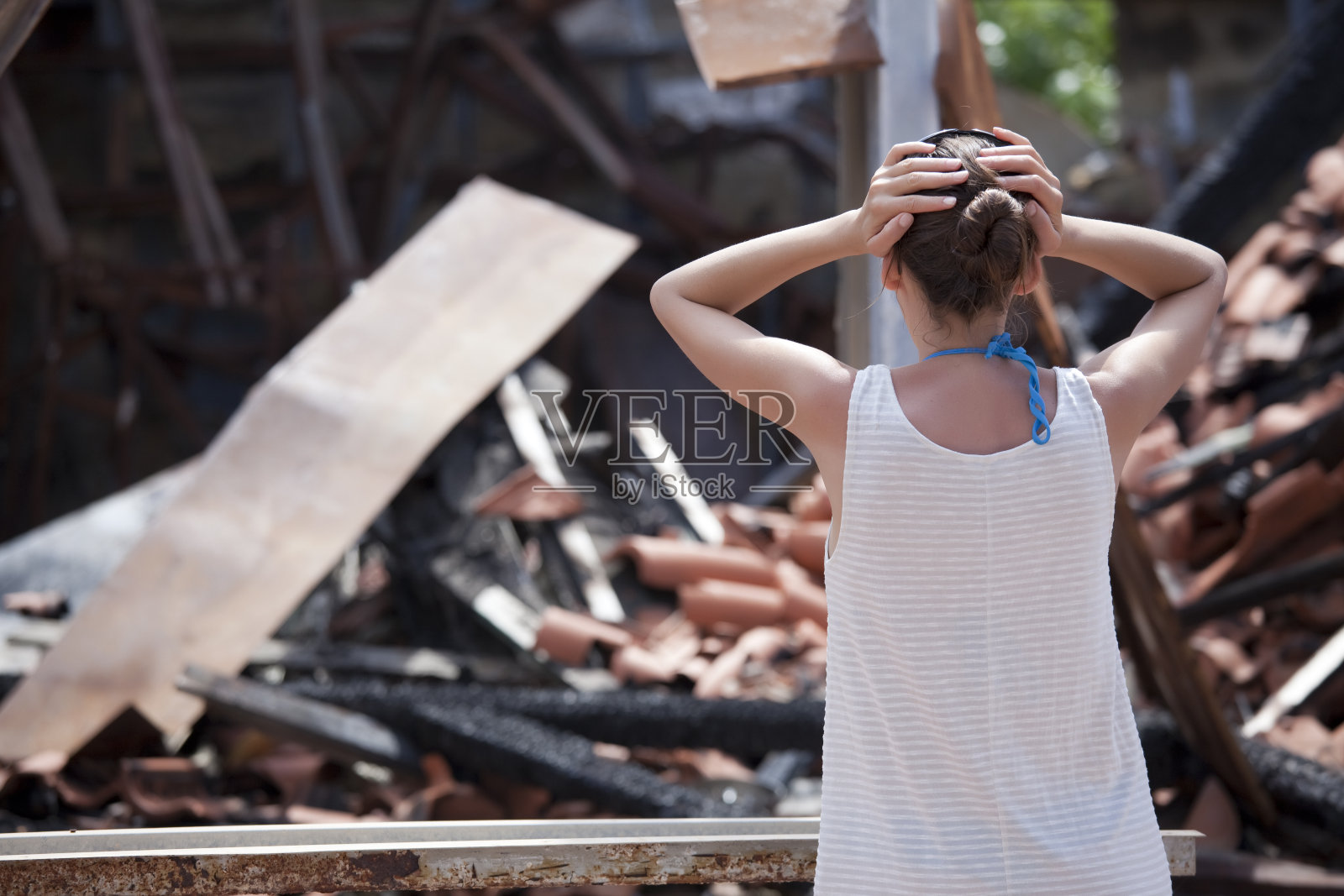 一个女人站在烧毁的房子前照片摄影图片