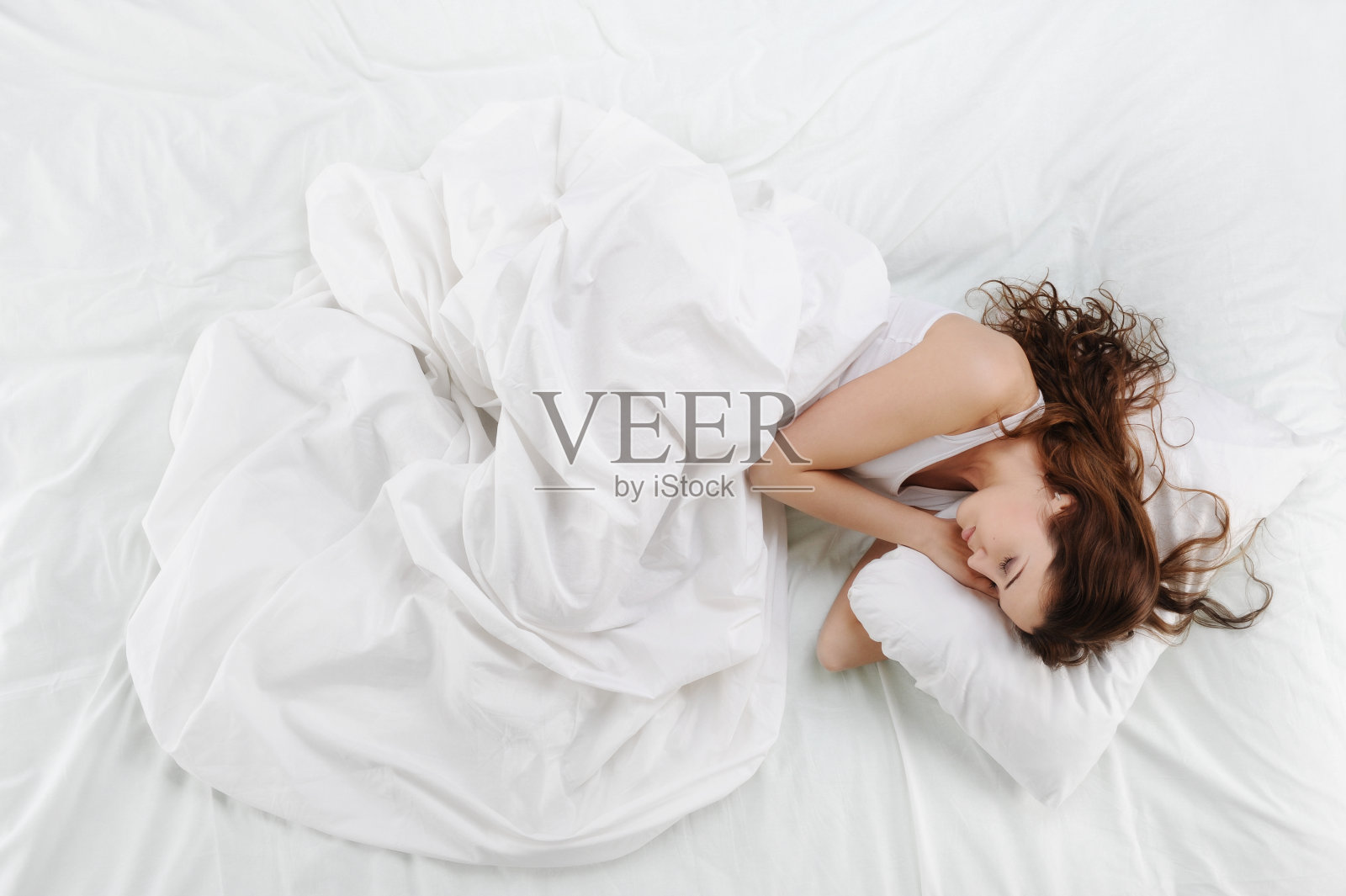 一个女人安静地睡在铺着干净白床单的床上照片摄影图片