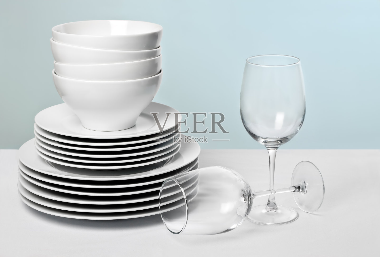 白色的盘子和水晶酒杯在不同的蓝色背景照片摄影图片