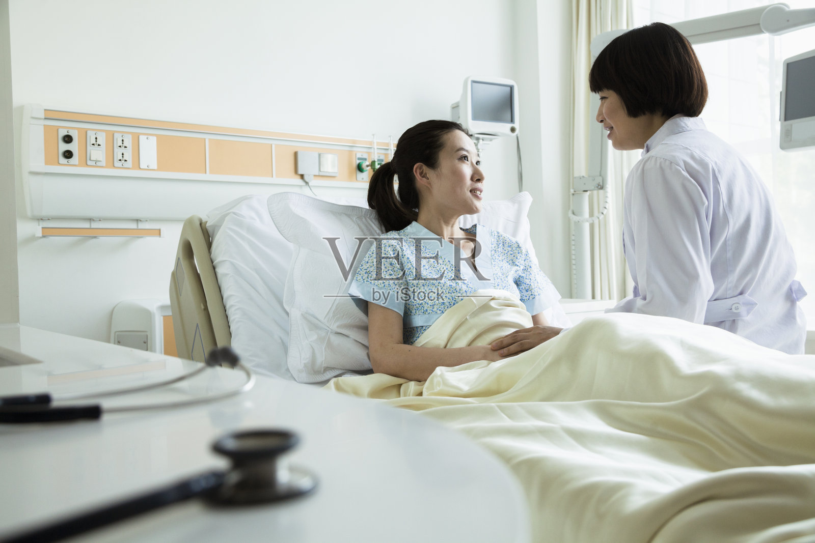 女亚洲医生与年轻的亚洲女性病人交谈照片摄影图片