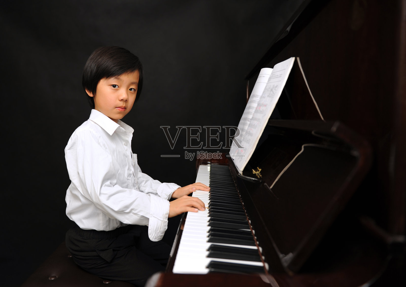 年轻的亚洲男孩在弹钢琴照片摄影图片