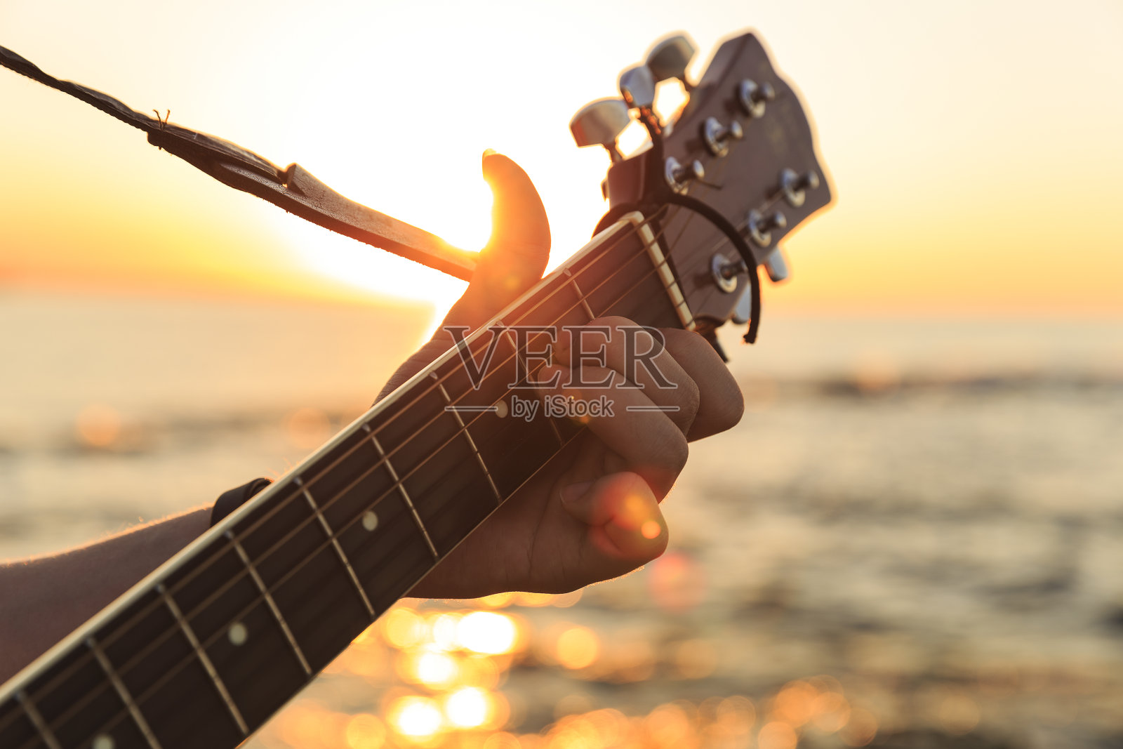 夕阳下弹吉他的年轻人(软焦点)照片摄影图片