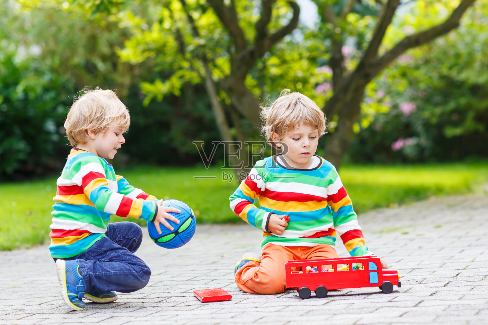 两个兄弟姐妹，孩子们在玩红色的校车照片摄影图片