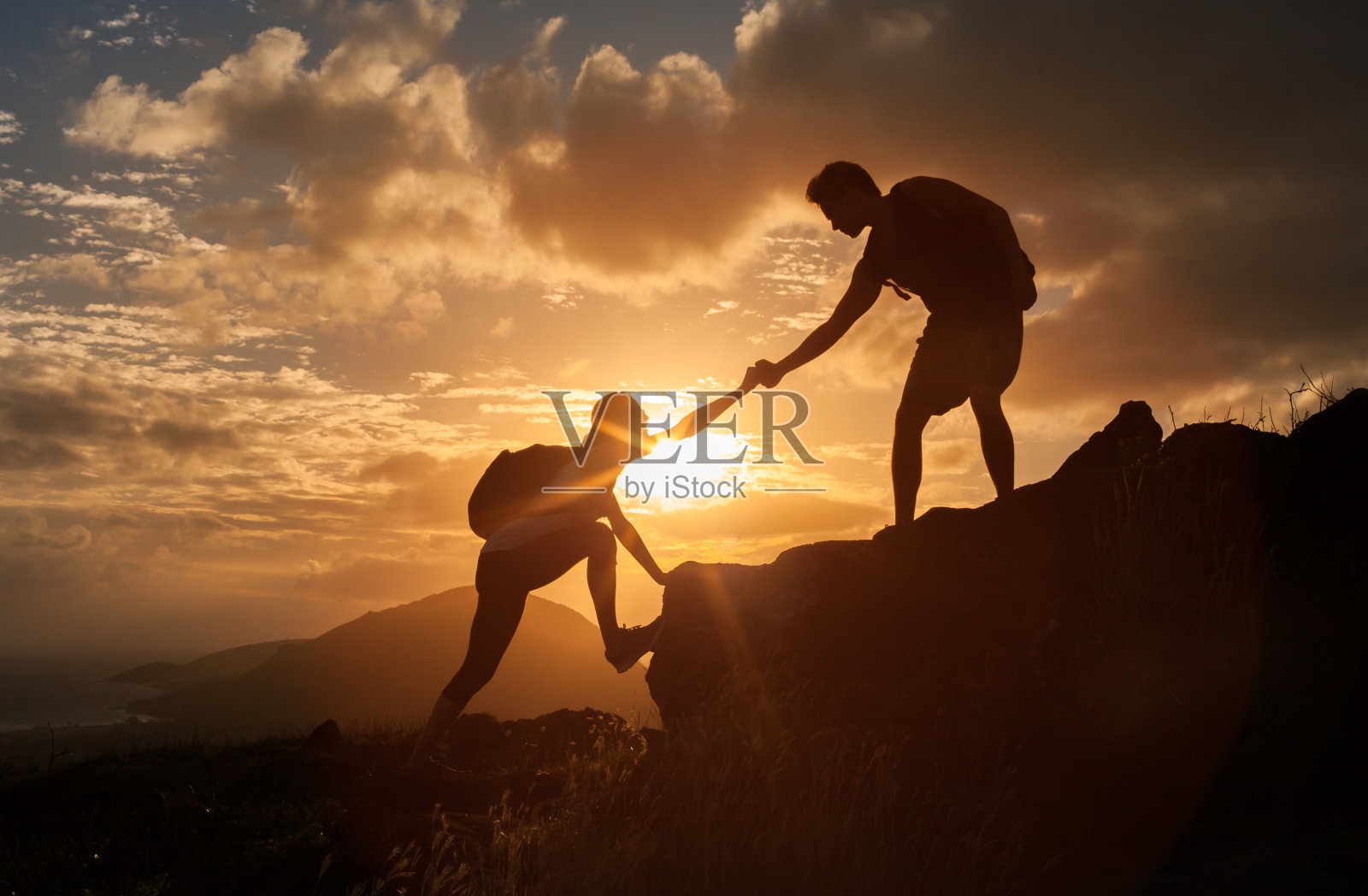 一男一女徒步者正在攀登悬崖，其中一人伸出援手。照片摄影图片