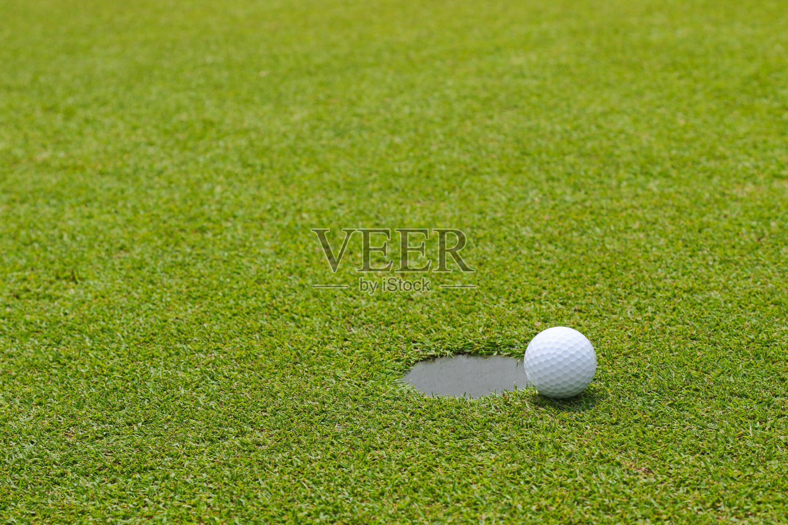 高尔夫球，靠近果岭的推杆杯照片摄影图片