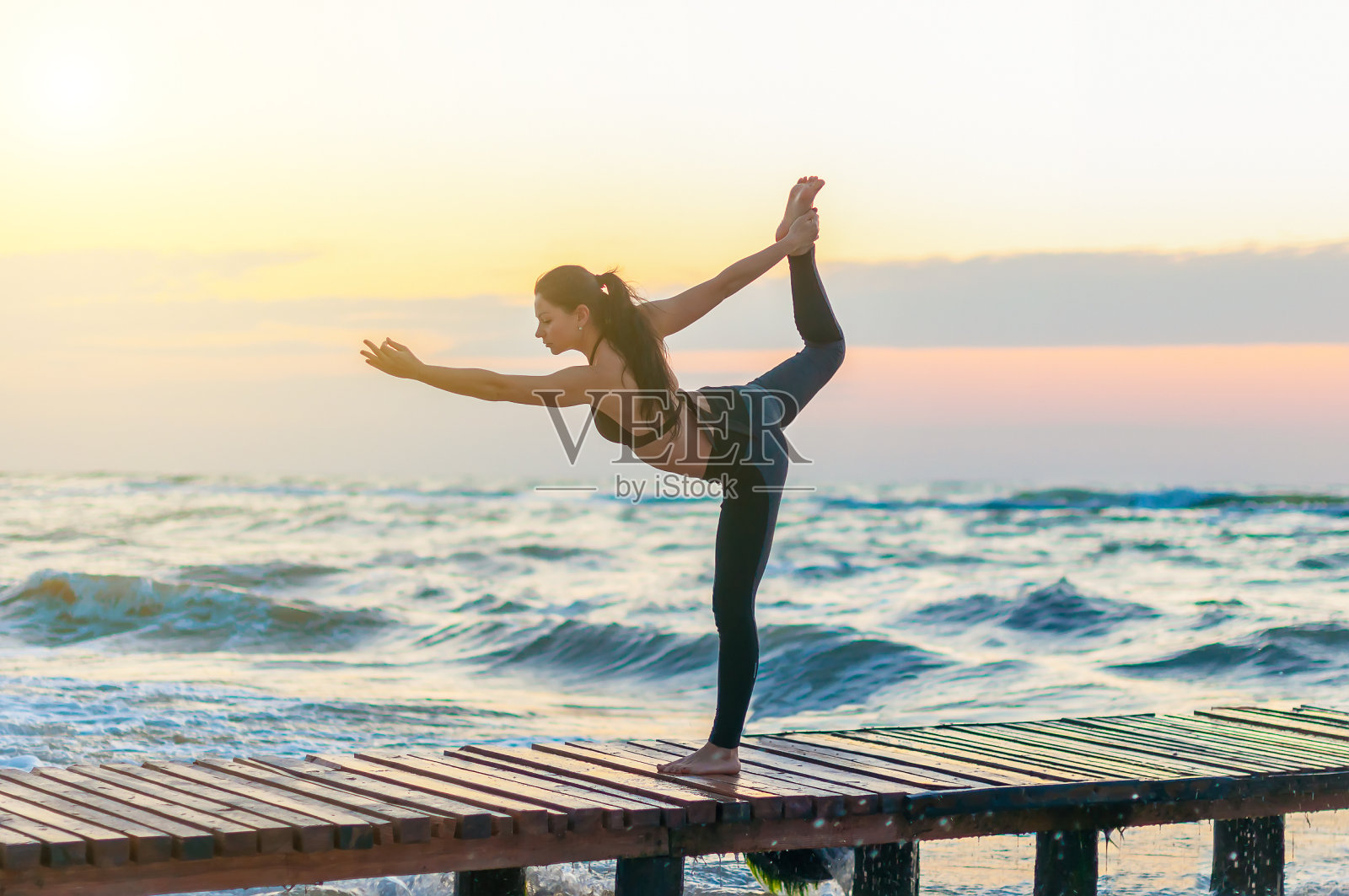 女子练习武士瑜伽姿势户外日落天空的背景照片摄影图片