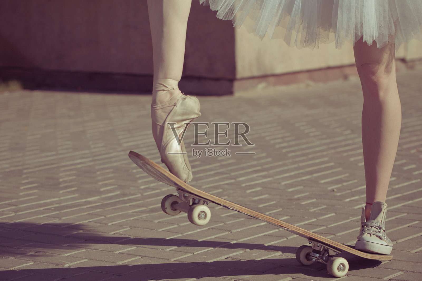滑板上芭蕾舞演员的腿。照片摄影图片