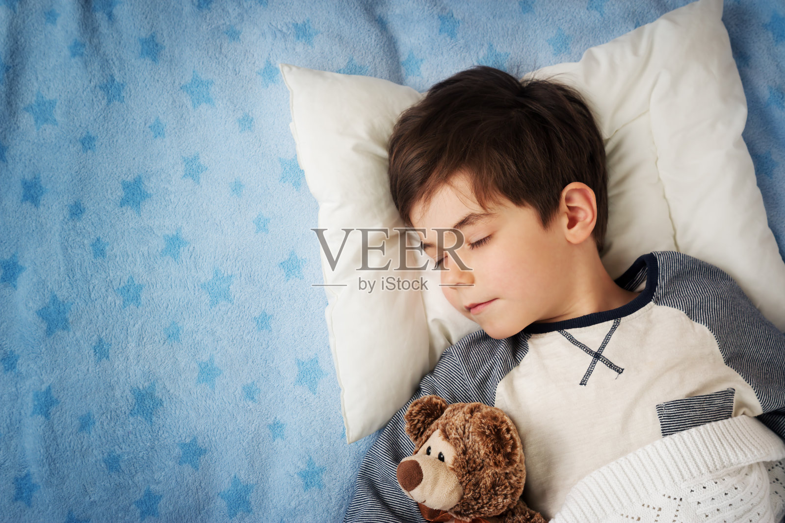 6岁的孩子睡在有闹钟的床上照片摄影图片