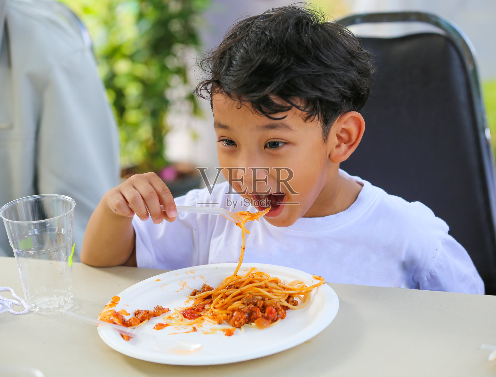 亚洲小男孩午餐吃番茄酱意大利面。照片摄影图片