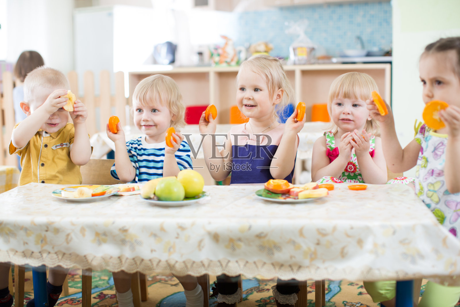 有趣的孩子在幼儿园或日托中心吃水果照片摄影图片