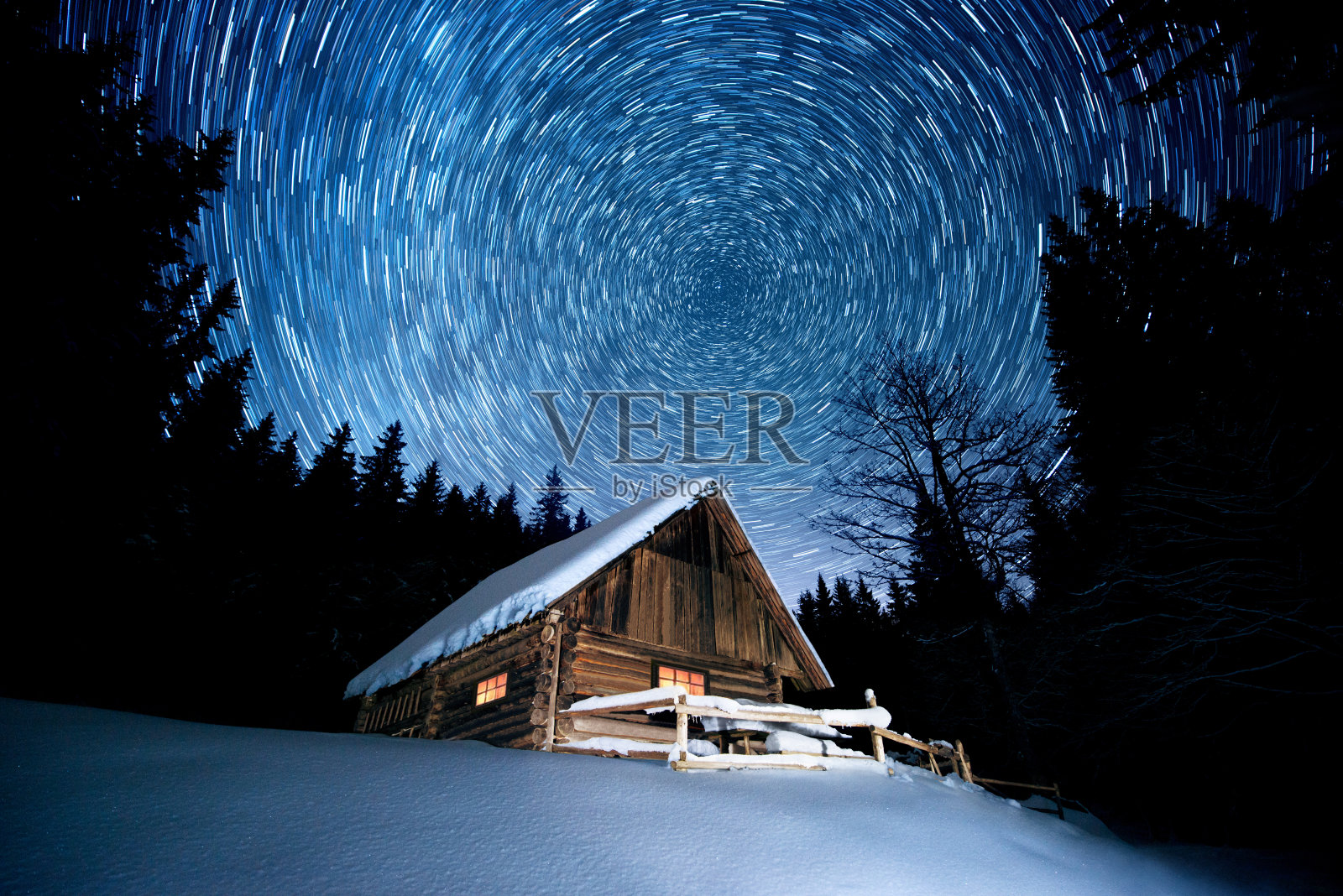 在冬天的森林里，星星在木屋上划过照片摄影图片