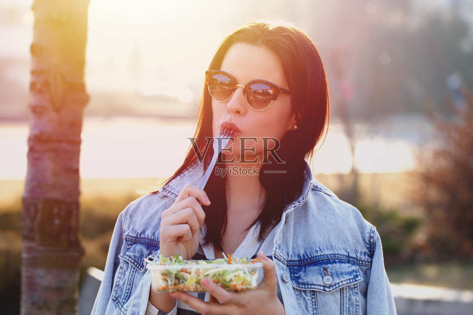年轻女子在户外拿着新鲜沙拉和叉子照片摄影图片