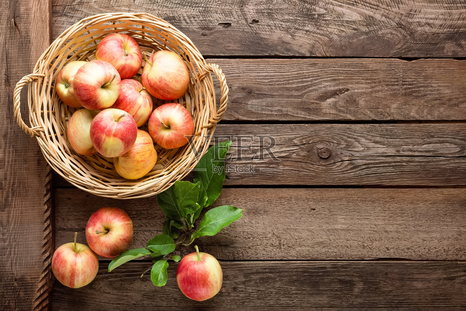 柳条篮子里的新鲜苹果放在木桌上照片摄影图片