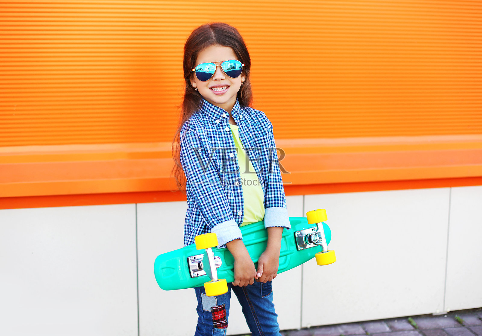 快乐时尚的小女孩的滑板在橙色照片摄影图片