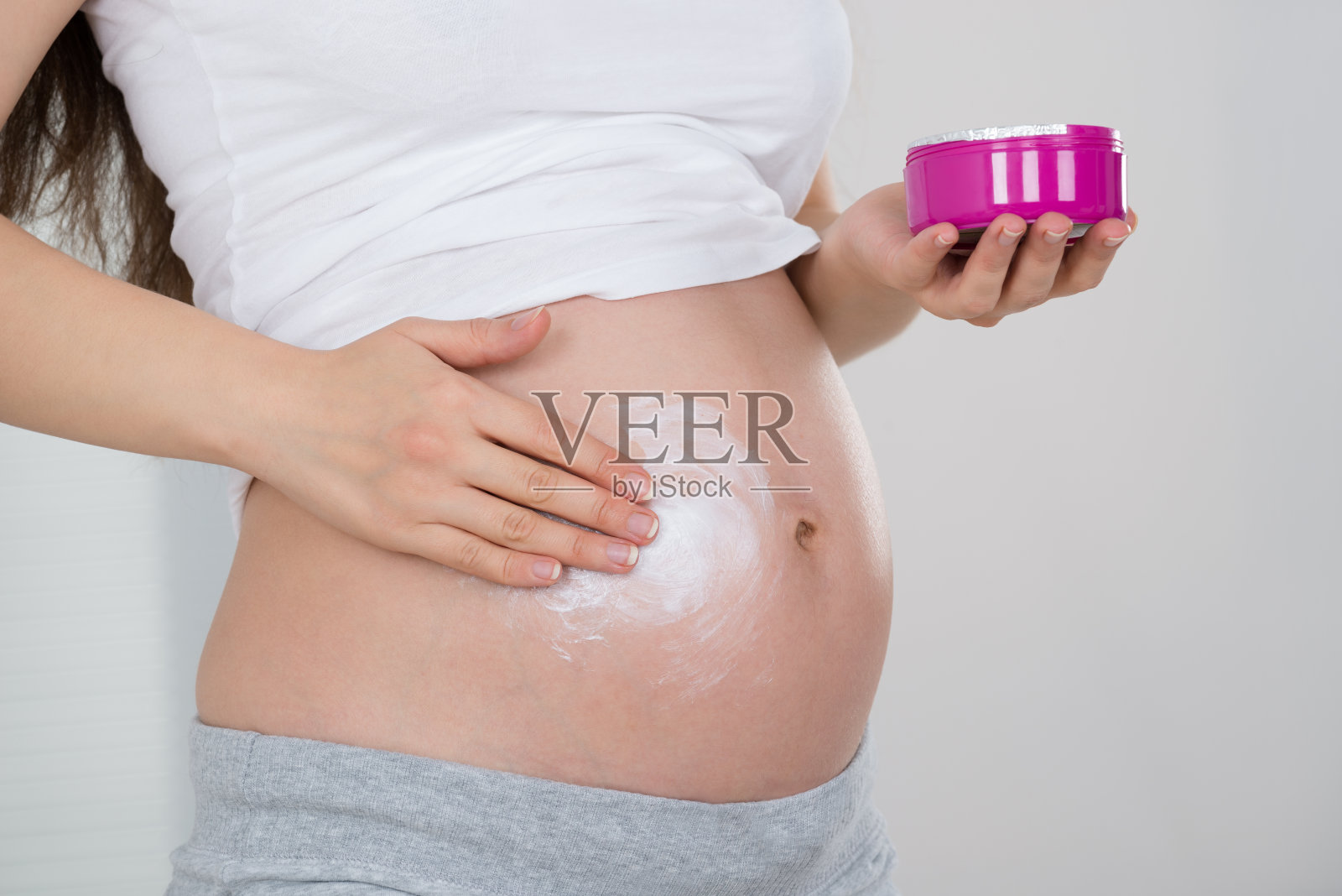 孕妇在她的肚子上涂霜照片摄影图片