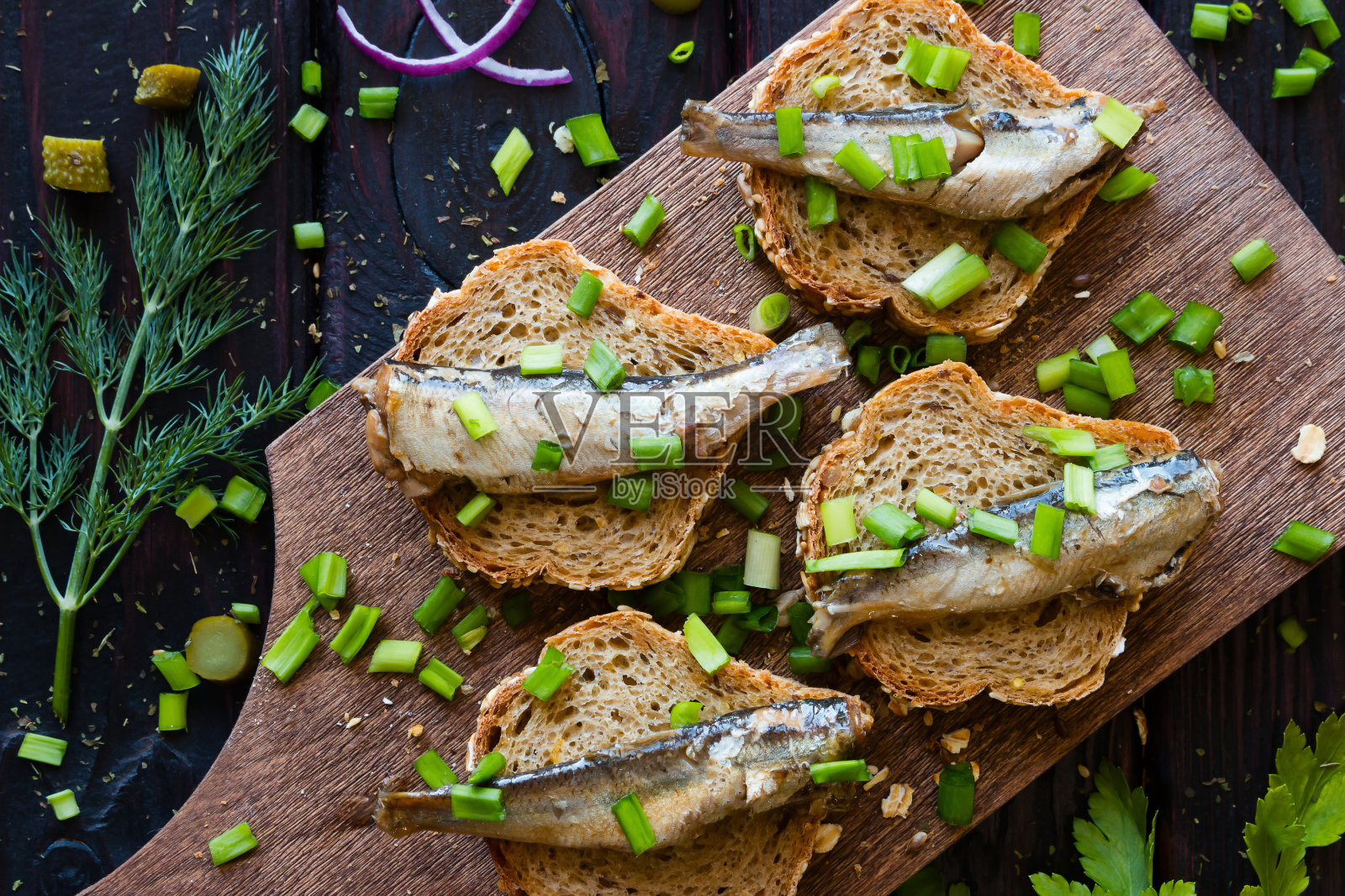 沙丁鱼三明治，在切菜板上撒上洋葱照片摄影图片