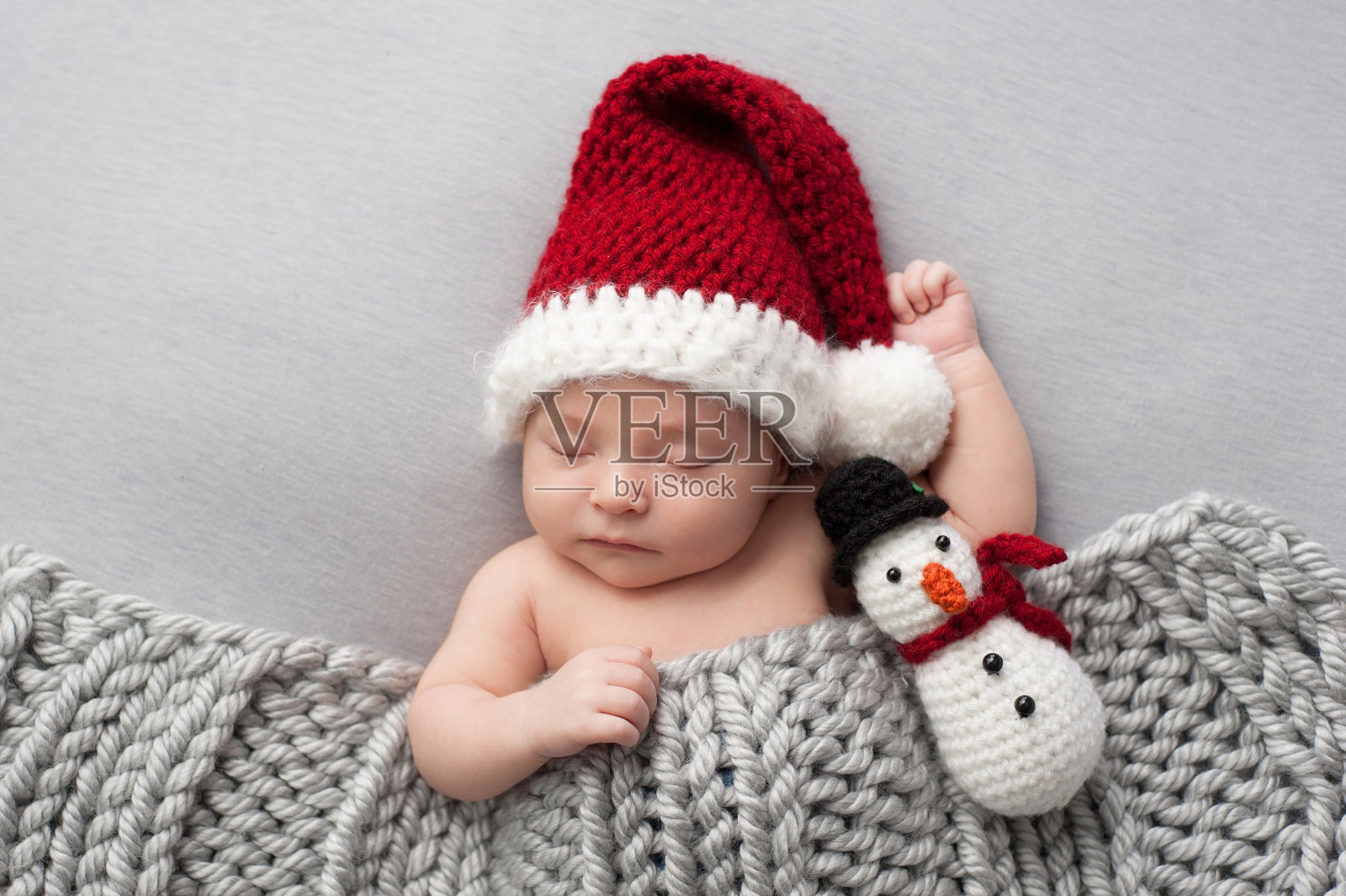 刚出生的男孩戴着圣诞帽和雪人毛绒玩具照片摄影图片