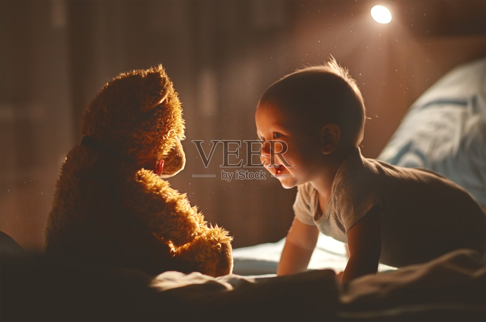 快乐的宝宝和泰迪熊在床上笑照片摄影图片
