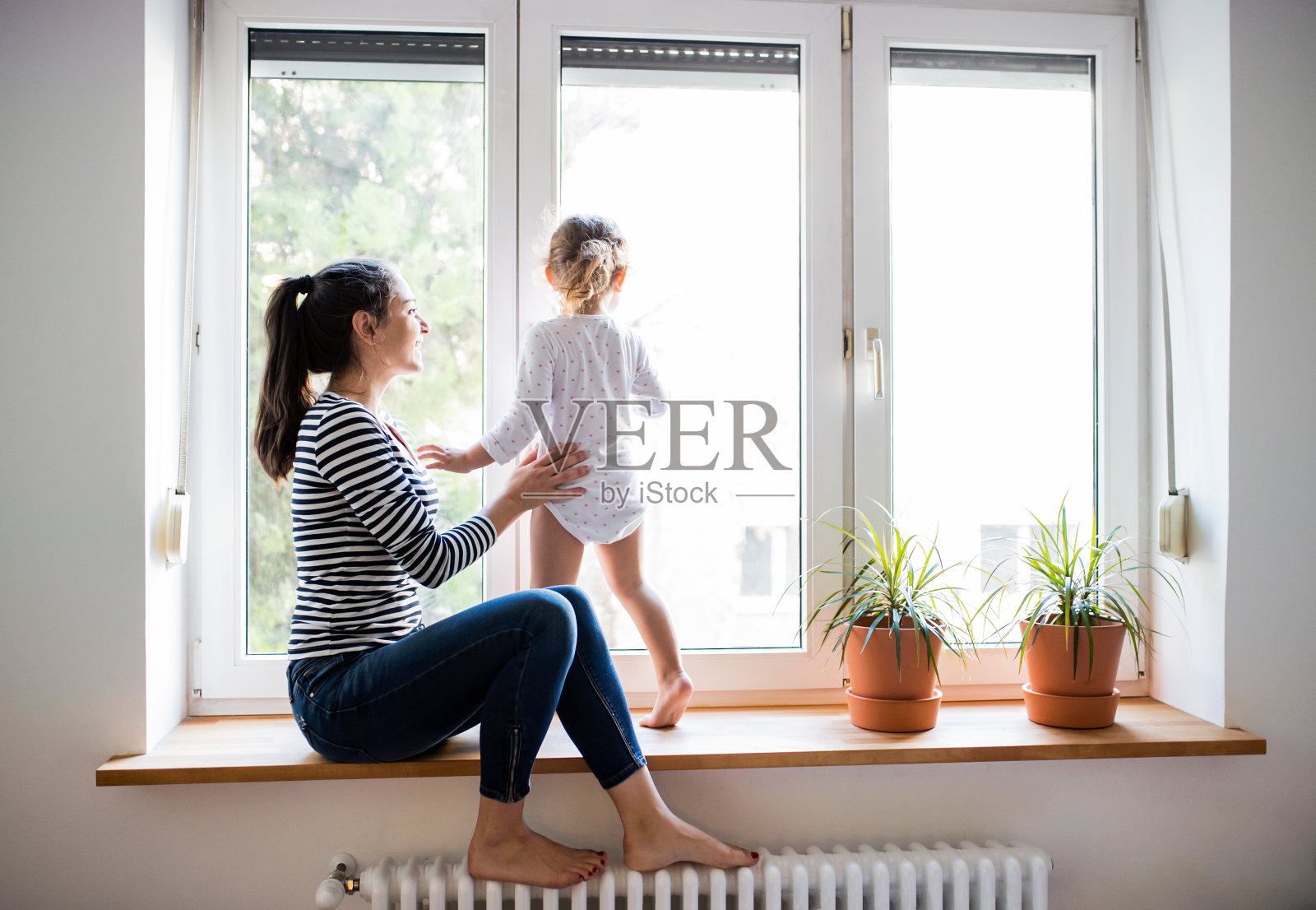 母亲和她的小女儿望着窗外照片摄影图片
