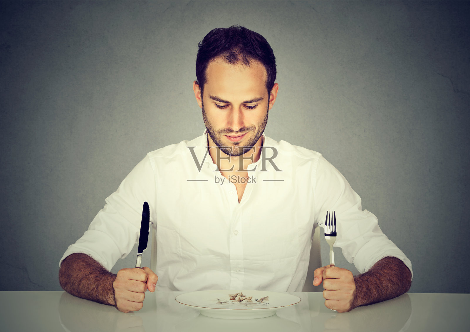 男人拿着刀叉在餐桌上看着空盘子照片摄影图片
