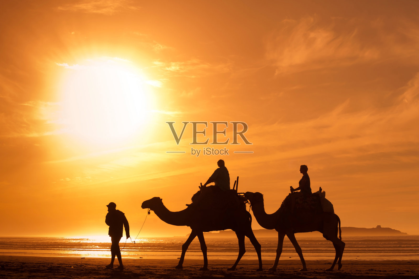 在非洲的旅游业，人们在海滩上骑骆驼照片摄影图片