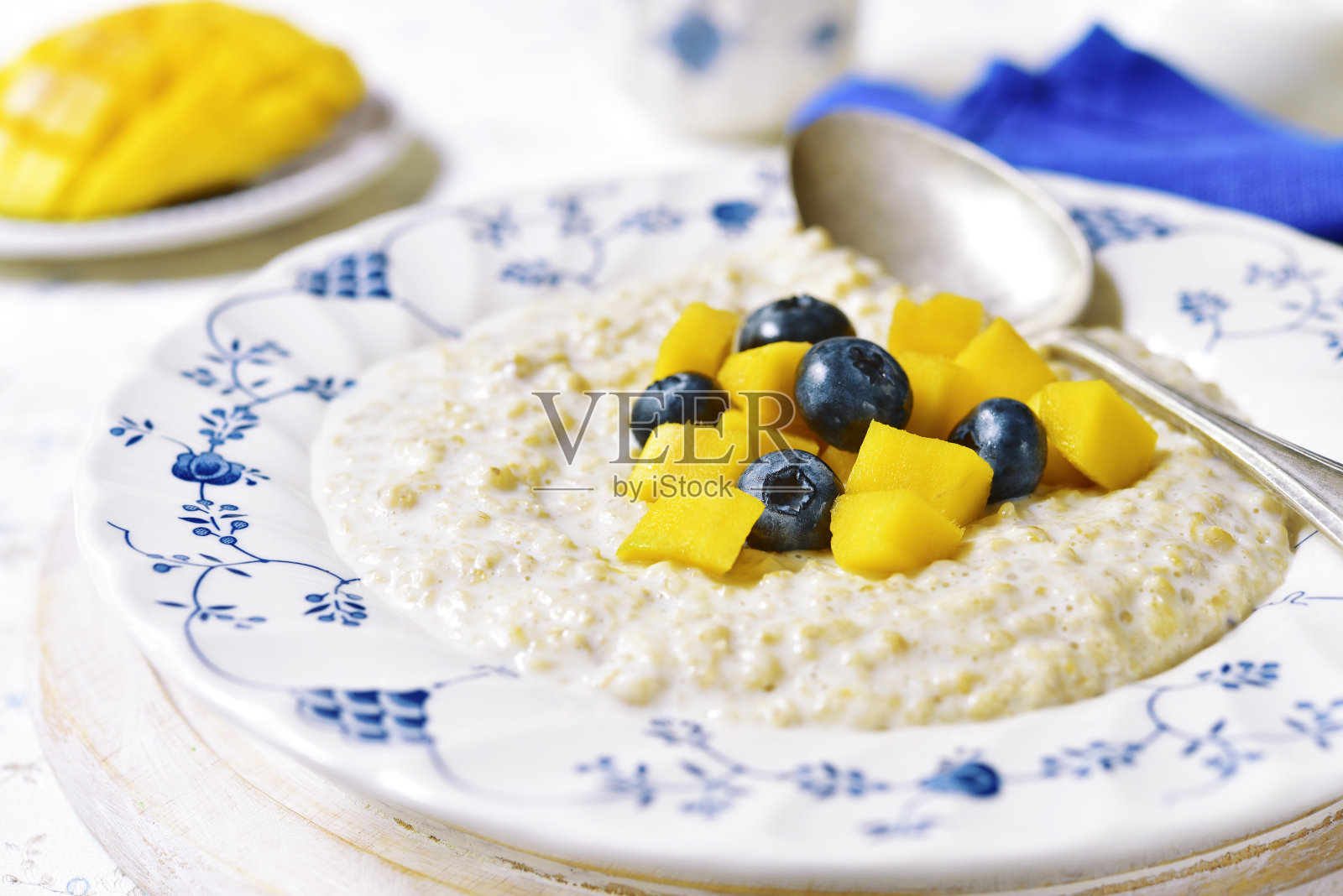 早餐燕麦粥配芒果和蓝莓。照片摄影图片