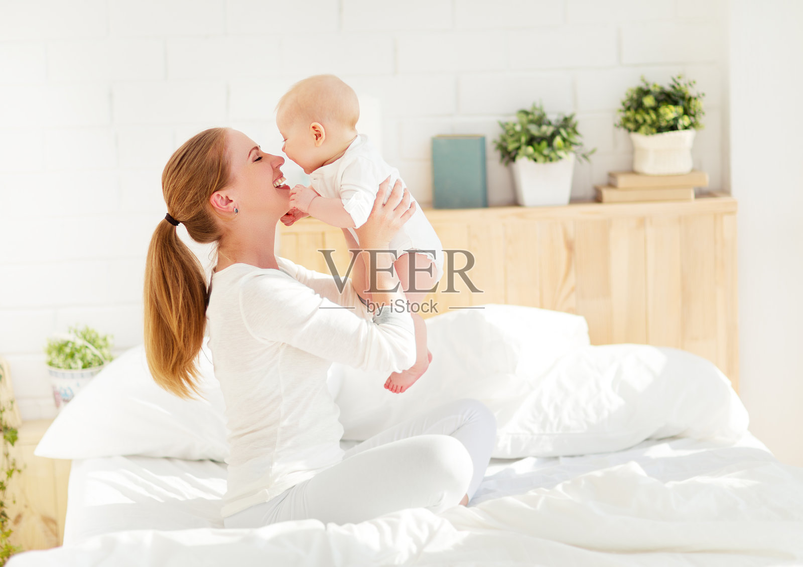 快乐的家庭妈妈和宝宝在床上玩耍和拥抱照片摄影图片
