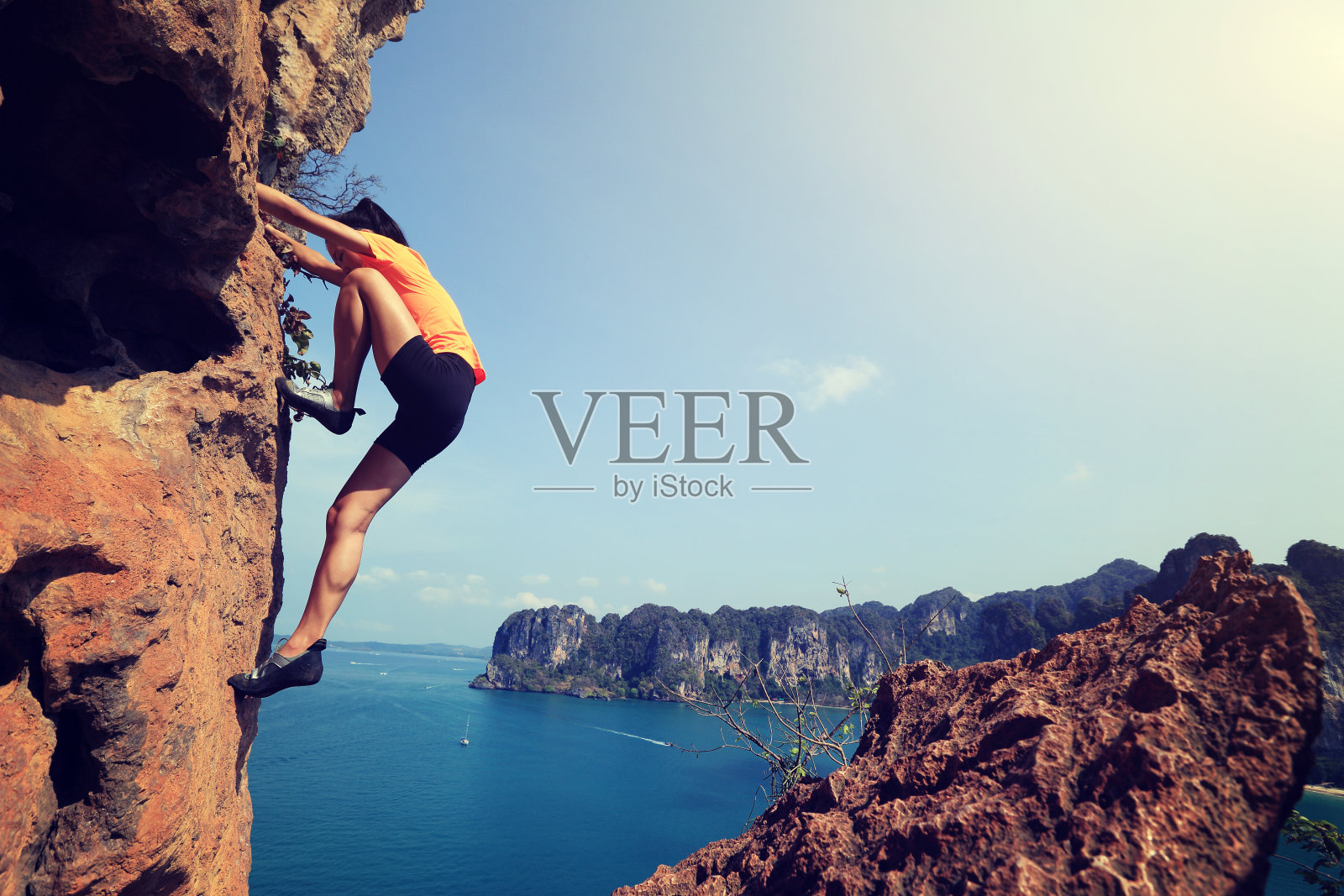 一名年轻女子攀岩者正在海边的山上攀岩照片摄影图片