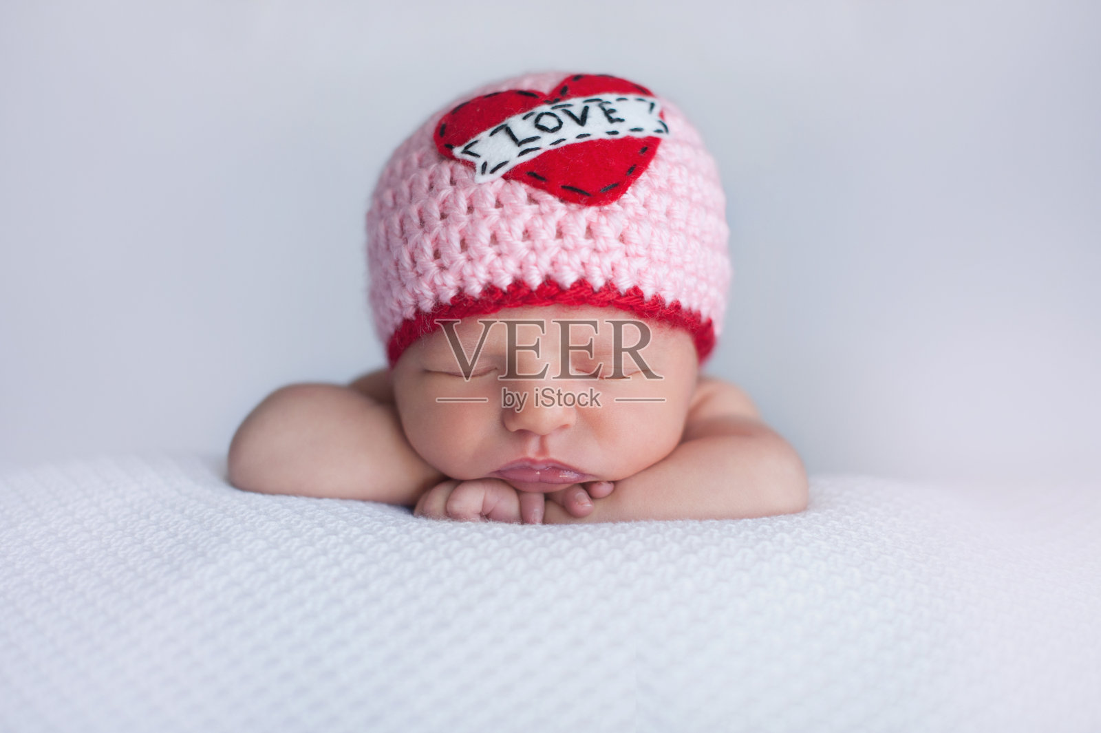 新生女婴戴着一顶“爱”帽照片摄影图片