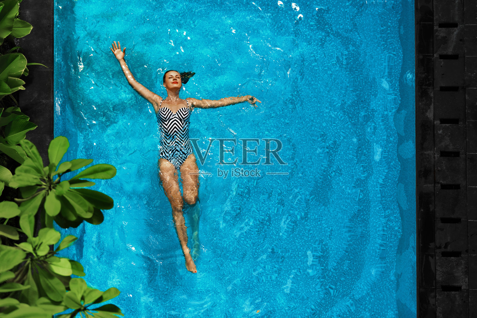 在游泳池水里放松的女人。暑假假期。照片摄影图片