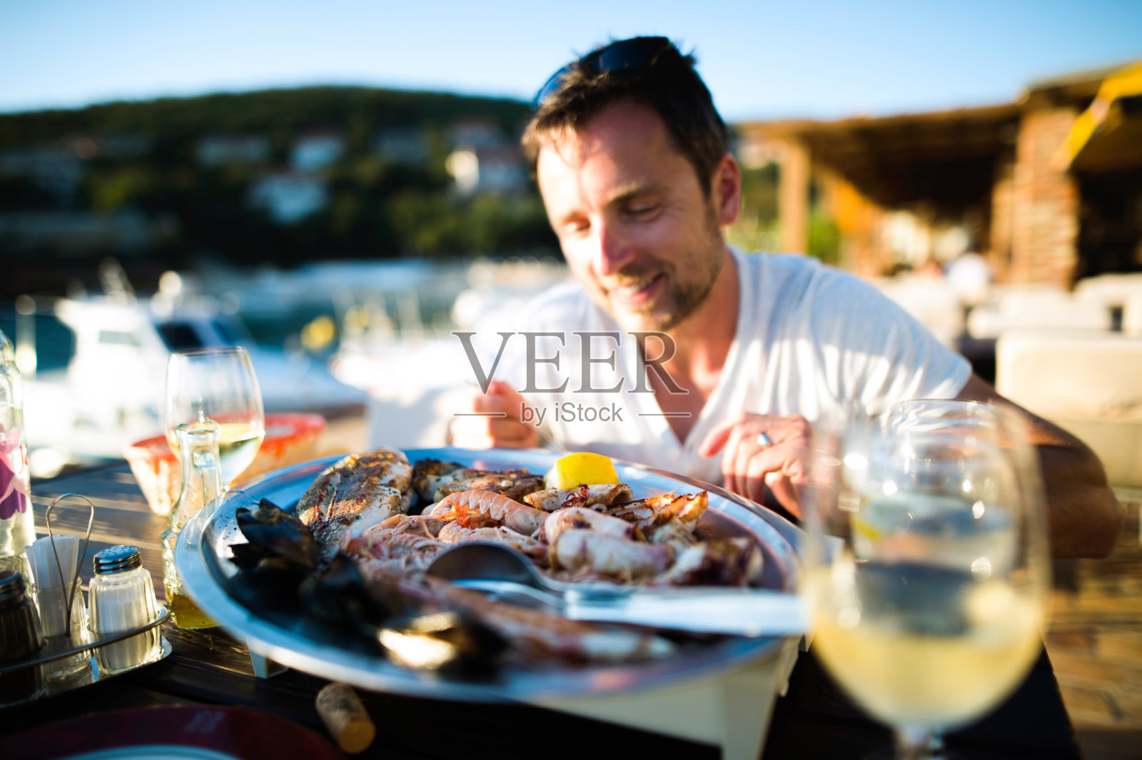 假日里的男人，在日落时分坐在外面，吃着海鲜照片摄影图片