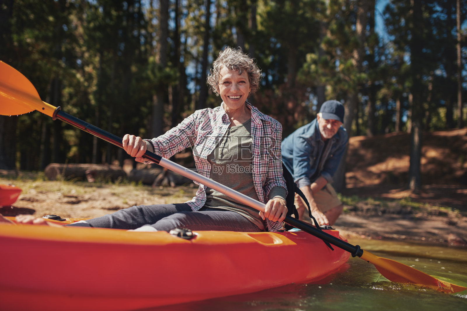 快乐的老妇人在湖上划着皮艇照片摄影图片